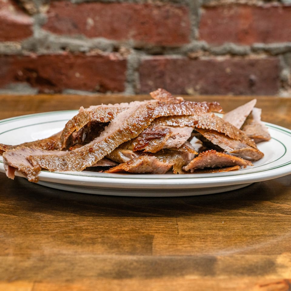 Thinly sliced gyro meat on a plate.